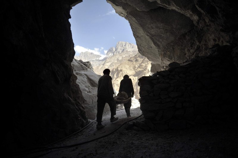 Two miners take out unnecessary large stones with a stretcher