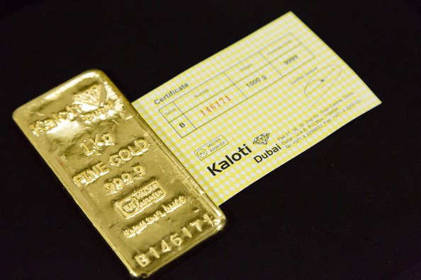 A finished one kilogram 24-carat gold bar stamped "Kaloti Dubai" sits displayed with a certificate confirming weight and quality after refining at the Kaloti Jewellery LLC factory in Sharjah, United Arab Emirates