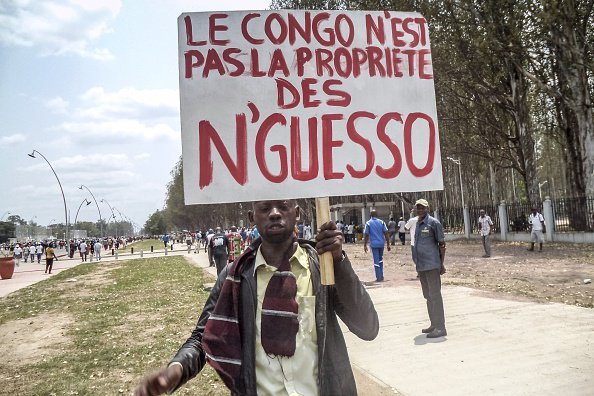 A man holds a placard reading “Congo is not the Sassou Nguessos' [private] property”