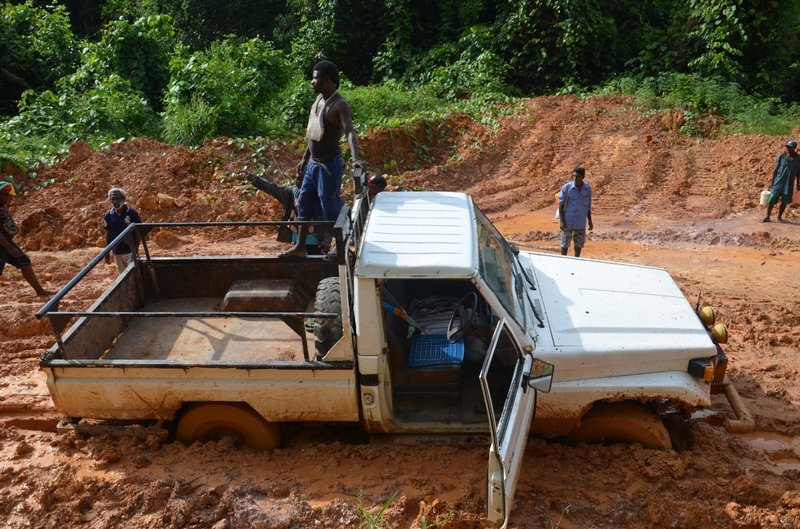 men surround truck bogged down on poorly maintained road in Papua New Guinea