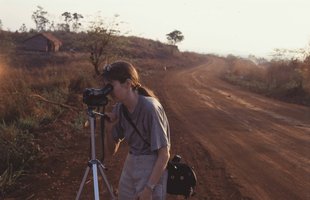 Global Witness Co-founder Charmian Gooch standing on road filming on camera on an early investigative trip