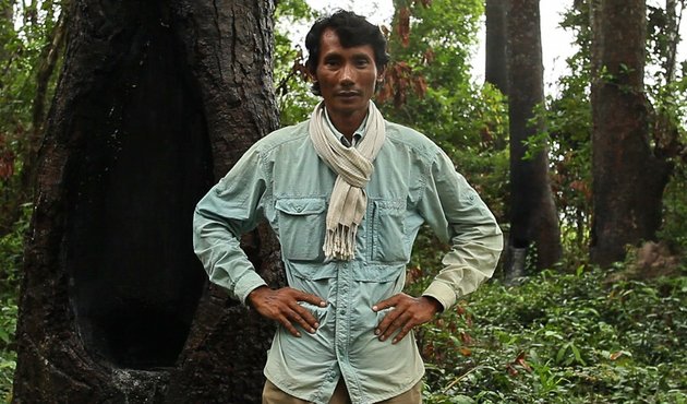 environmental defender Chut Wutty stands with hands on hips in the Cambodian forest he is campaigning for against logging