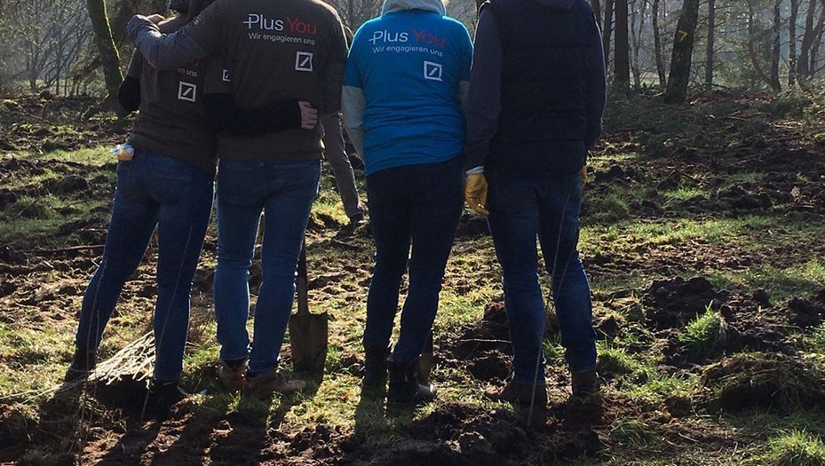 Deutsche Bank employees pose with a spade during a volunteering project to plant trees in Germany