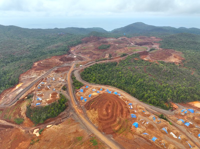 View from above - brown hills of earth with tiny diggers and sharp edges where the forest is being cut away