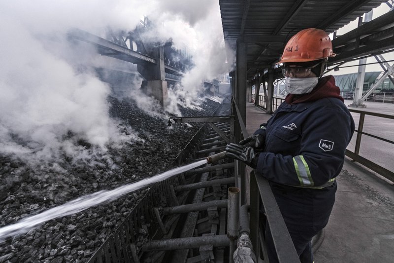 A worker uses a hose to cool down freshly produced coke at the ArcelorMittal steel plant in Kryvyi Rih, Ukraine