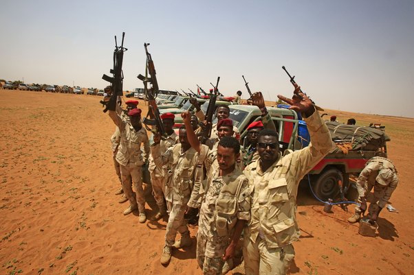 RSF celebrate in Gouz Abudloaa after the capture of migrants trying to cross into Libya, surrounded by Toyota vehicles mounted with machine guns. © RASHRAF SHAZLY/AFP via Getty Images