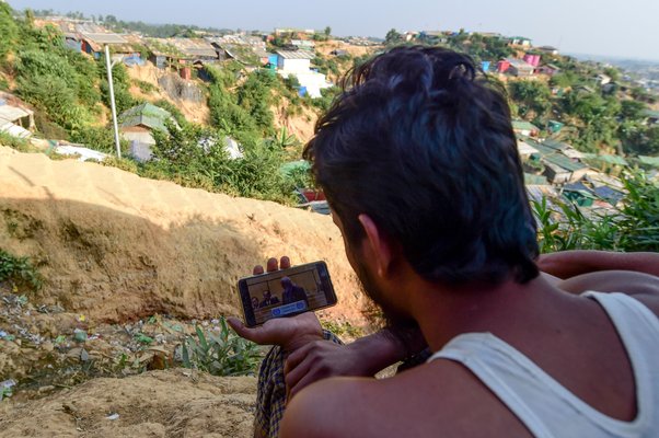 A Rohingya refugee looks at his phone