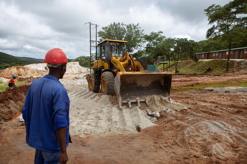 A foreman looks on as a bulldozer works on the slippery road at Arcadia Lithium mine in Goromonzi, Zimbabwe