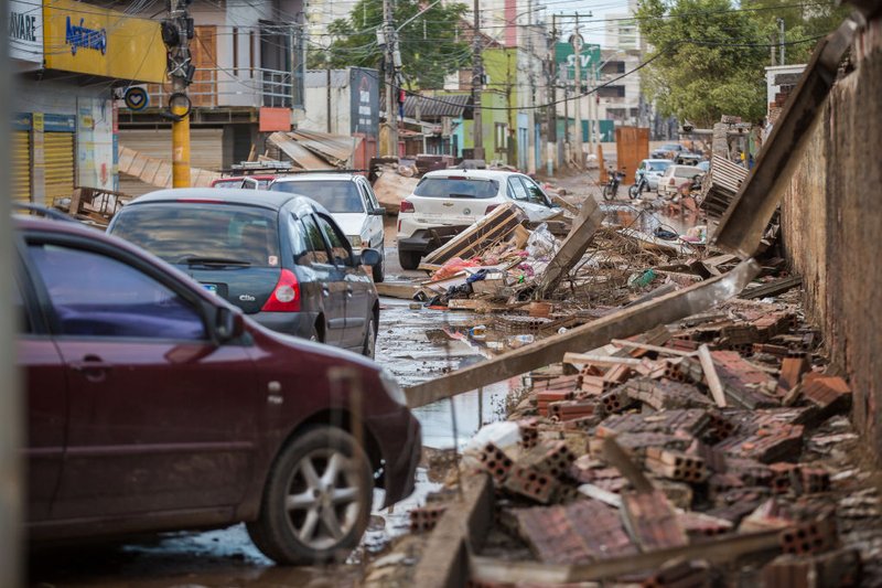 Cars drive next to debris in a flooded residential condominium at Sao Miguel neighborhood in Sao Leopoldo, Brazil