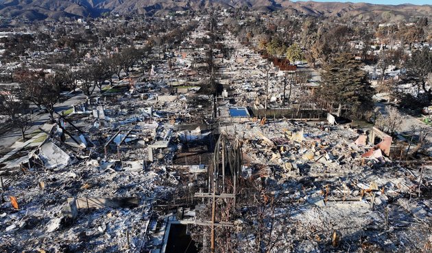 An aerial photograph of blackened buildings and scorched trees following the aftermath of the LA fires in January 2025.