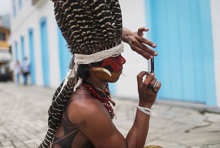 An Indigenous activist photographs another Indigenous community member after a protest march for Indigenous land rights in Brazil. Land and environmental defenders often rely on digital platforms to spread awareness about their campaigns
