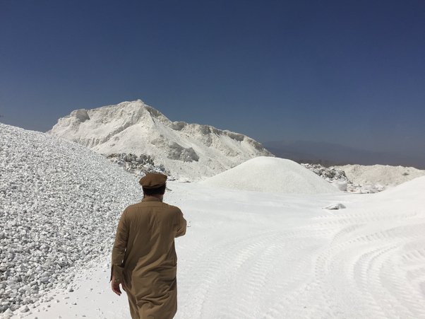 Man walks among piles of talc at a processing plant near Jalalabad