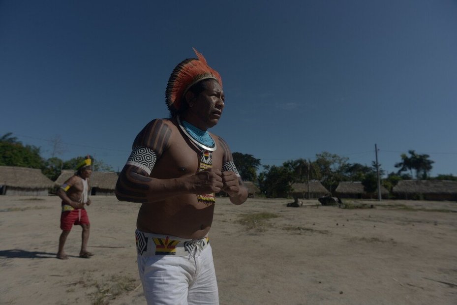 Indigenous leader from the Kayapó community, and another member of the community, perform singing and dancing around Baú village, Pará, Brazil