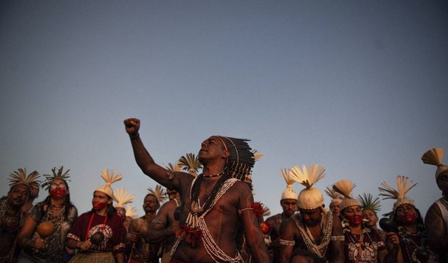 indigenous people gather together and raise fist to sky