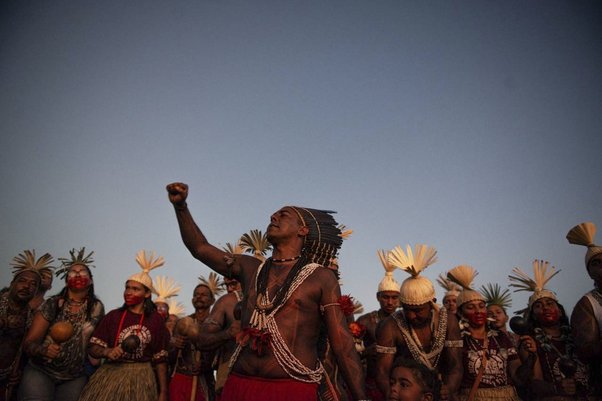 indigenous people gather together and raise fist to sky