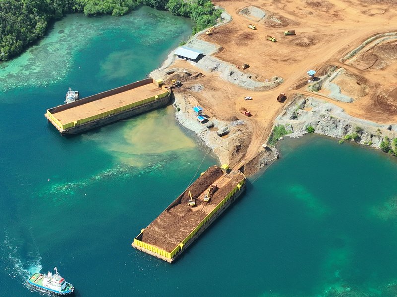 Close view of nickel barges being loaded and leaking sediment turning the blue water brown
