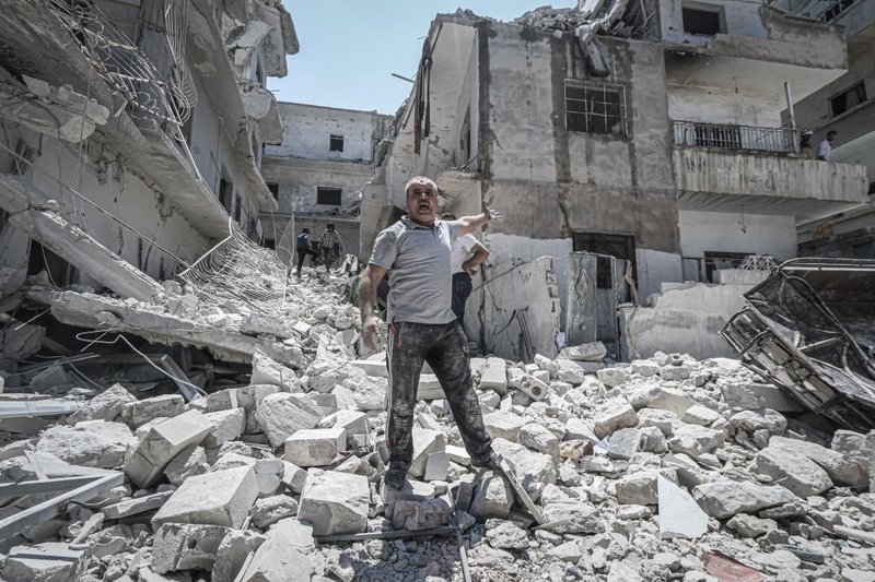 Man in destroyed buildings debris following airstrike in Idlib, Syria