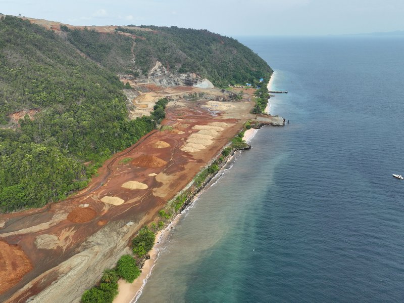 View from above of deforestation and mining sediment bleeding into the sea staining it brown