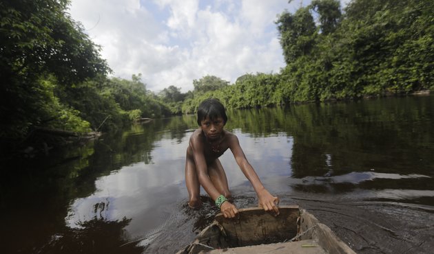 A member of the indigenous Ka'apor community pushing a boat down the river in Brazil’s Alto Turiaçu reserve