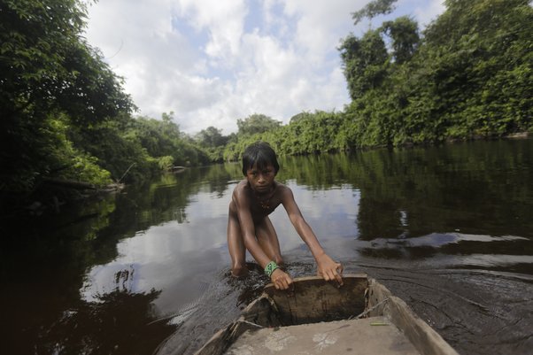 A member of the indigenous Ka'apor community pushing a boat down the river in Brazil’s Alto Turiaçu reserve