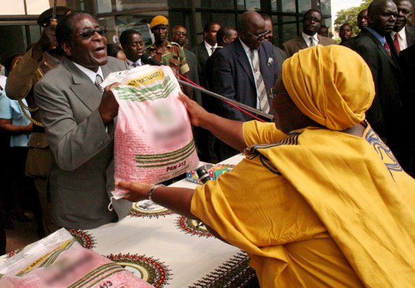 Former President, Robert Mugabe, hands out maize seed to a Zanu PF supporter at party headquarters in Harare, 2008. Aaron Ufumeli/EPA/Shutterstock