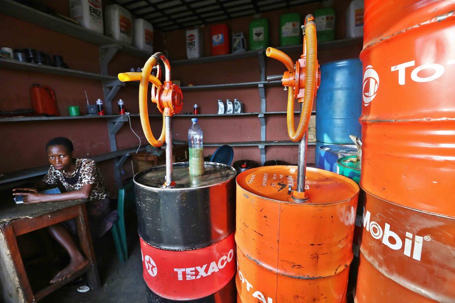 A street vendor waits for customers to buy oil from a roadside store in Port Harcourt, Nigeria.