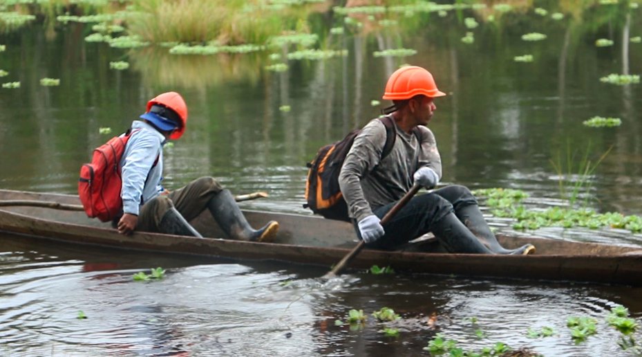 two OSINFOR inspectors float down the river on boat in Peru forest