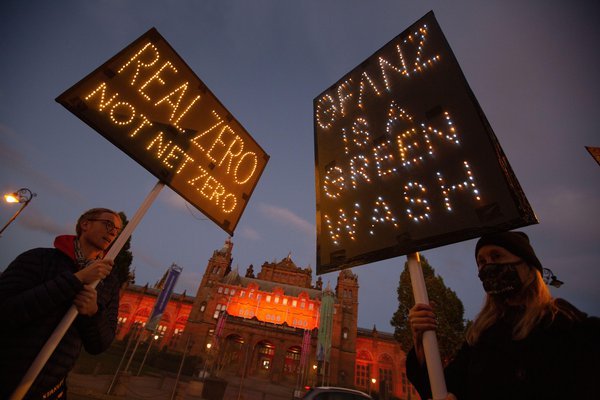 Protestors holding up placards saying "Real zero net zero" and "Gfanz is greenwash" at COP26 in Glasgow, November 2022