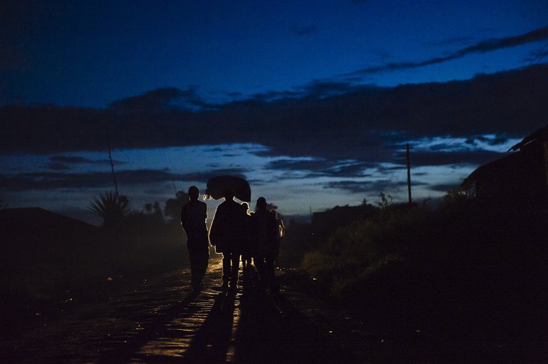 People walk at dusk through the town of Mwenga in South Kivu, DRC