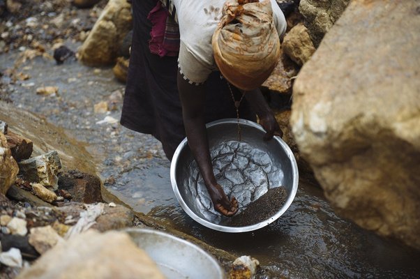 A lady pans rocks for cassiterite in a stream around the D23 cassiterite mining site in South Kivu province in the east of the Democratic Republic of the Congo on April 4, 2015.