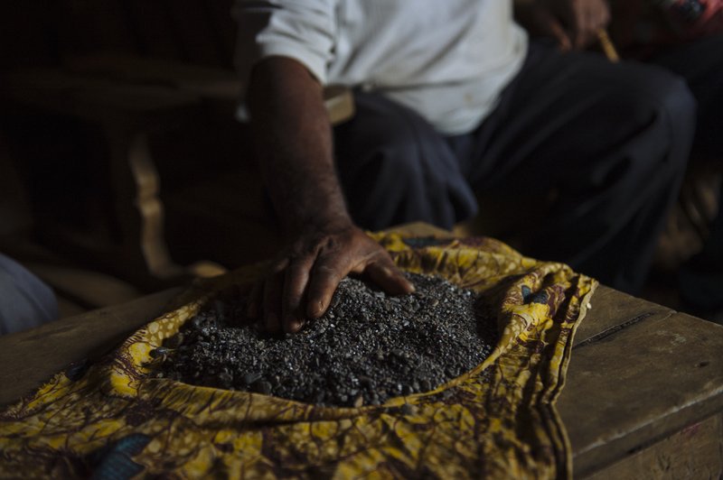 A miner spreads out a small stock of coltan