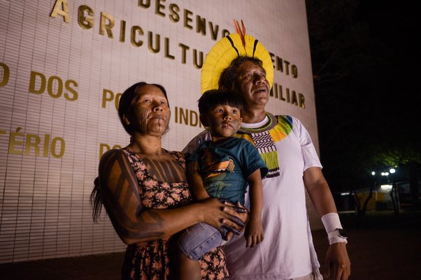 Doto Takak Ire, Indigenous leader of the Kayapó People, and his family in front of the Ministry of Indigenous Peoples with a sign saying “Indigenous peoples, future", in Brasilia, on 9 June 2023. (Karina Iliescu / Global Witness)