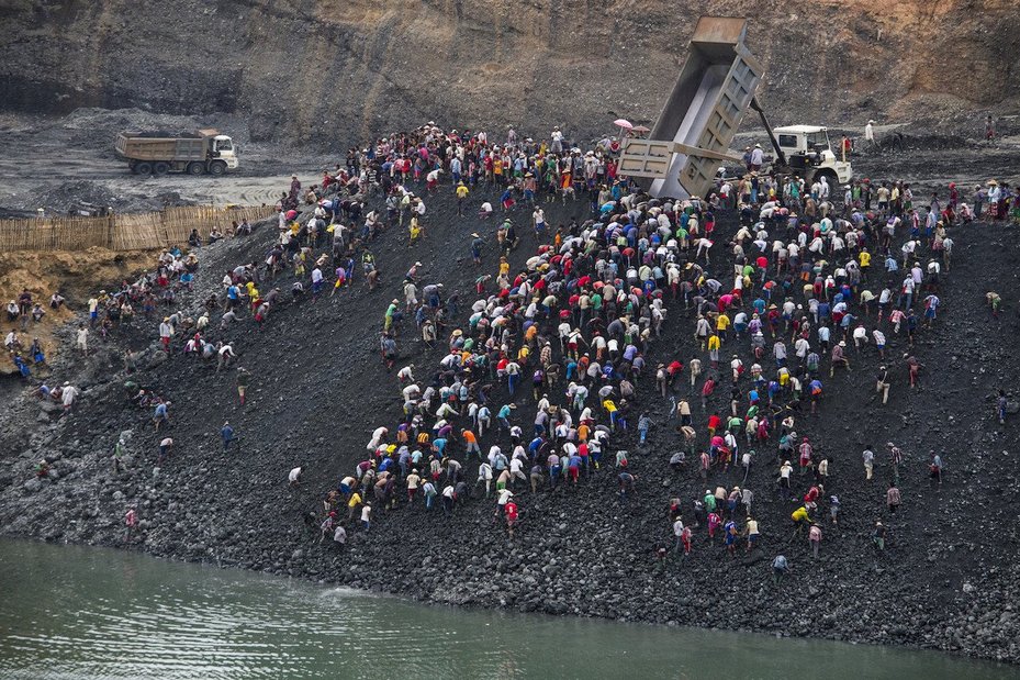 Small-scale miners search for stone as dump trucks from Myanmar Sein Lei Aung mining company dump waste in Hmaw Si Zar