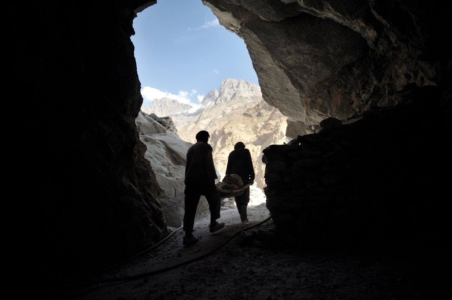 Two miners carry lapis stones.