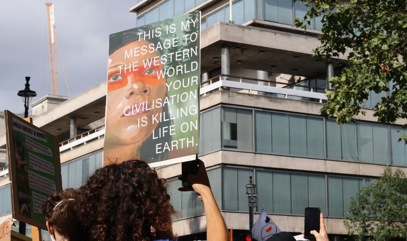 photo of a sign reading: THIS IS MY MESSAGE TO THE WESTERN WORLD YOUR CIVILISATION IS KILLING LIFE ON EARTH