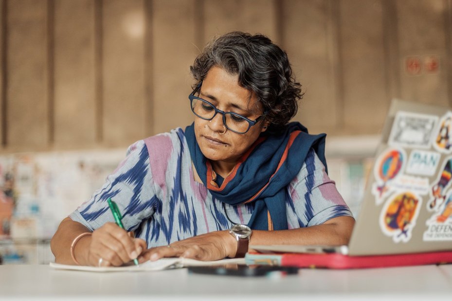 portrait of Sharanya, a defender from India who has faced digital threats, writing in notebook