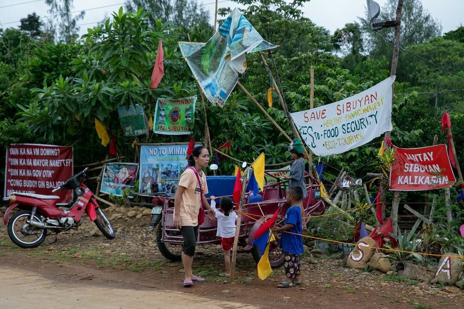 Residents walk past signs outside a protest camp in Sibuyan Island, Romblon province, central Philippines