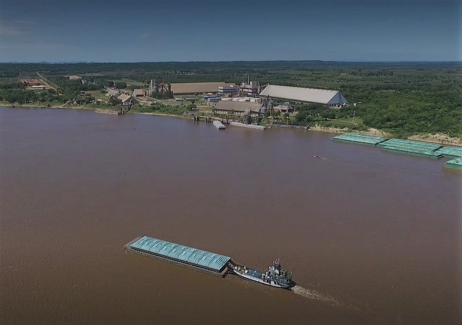 A soy barge heads upstream past the Caiasa soy port in Paraguay