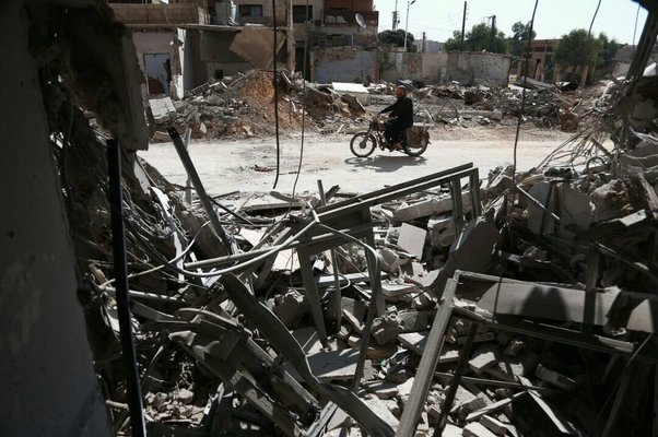 person riding motorbike through streets in Syria