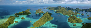 A dramatic aerial view of the limestone peaks of Wayag, vivid turquoise and green