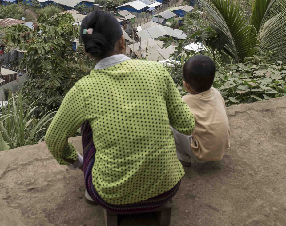 Villager sits with her child watching the operations of one of a major jade company