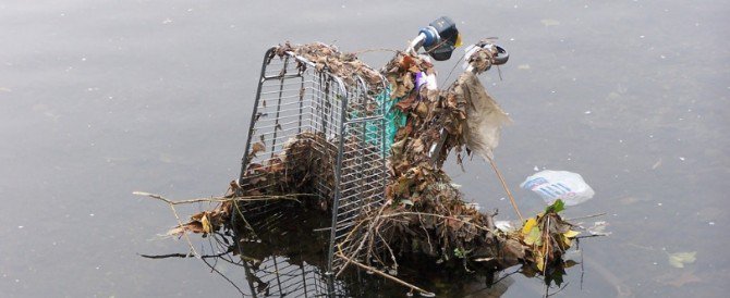 A shopping trolley in a river, full of rubbish