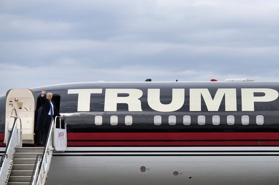 trump boarding plane with trump logo emblazoned on side