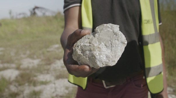 A worker holds a lump of lithium ore in Manono, DRC