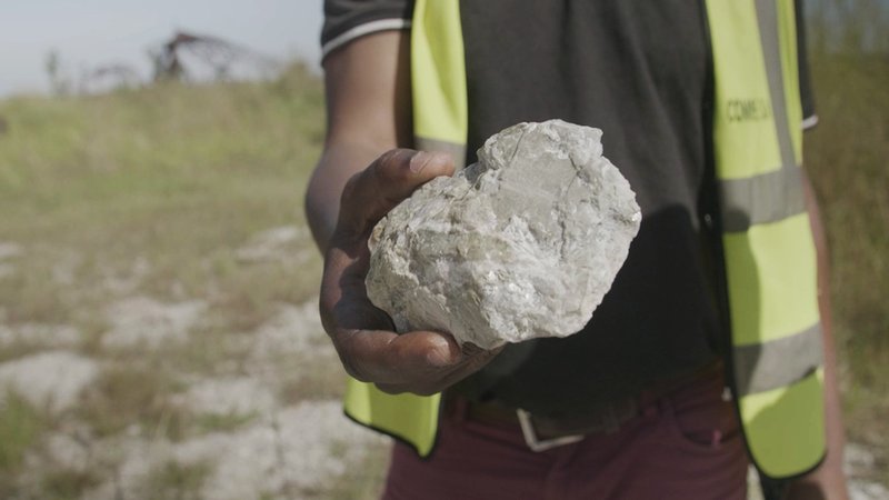 A worker holds a lump of lithium ore in Manono, DRC